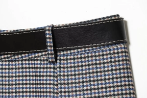 Detail of houndstooth plaid fabric with black leather belt and precise stitching