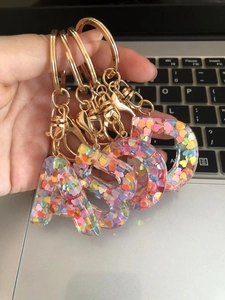Close-up of letter A-D keychains made of clear resin with colorful heart sequins