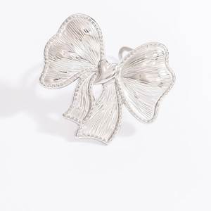 Detail view of silver bow-shaped stainless steel ring with intricate hollow texture