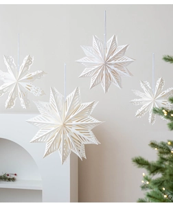 Detail of cream paper cutout snowflake stars hanging on a festive Christmas tree background