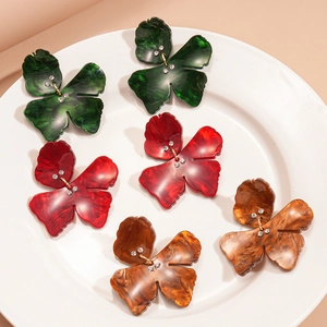 Resin clover earrings with rhinestones in green red and amber on a ceramic tray