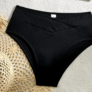 Detail of black high-waisted ribbed bikini bottoms with stylish V-shaped cross waist design