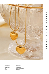 Close-up of dual 18K gold plated heart necklaces on a crystal glass bowl edge