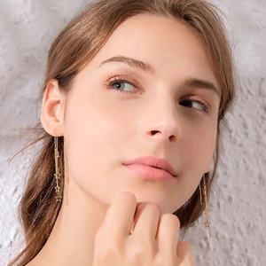 Long gold tassel earrings with star charms on a model, featuring fine link chains