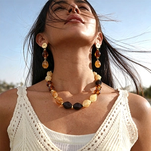 Detail of vintage amber resin jewelry set with faceted beads against a blue sky