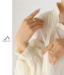 Detail of gold woven texture stainless steel ring worn on model with elegant style