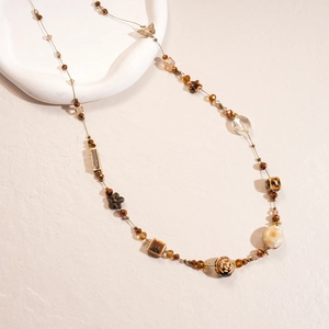 Detail of vintage beaded necklace featuring brown glass butterfly and star charms