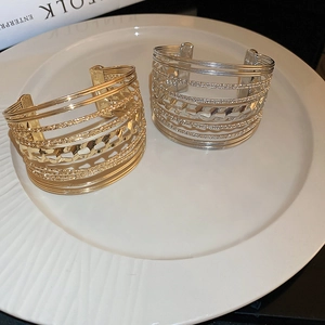 Detail view of multi-layer hollow geometric open bangles in gold and silver metal finishes