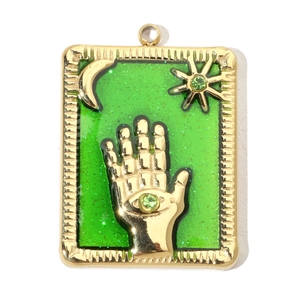 Detail of a vintage gold pendant featuring a hand with eye and green enamel background