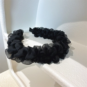 Detailed view of layered black organza pleats on a voluminous mesh headband