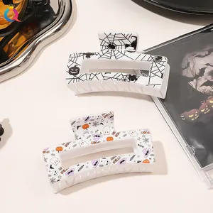 Close-up of Halloween acrylic hair claws with spider web and festive pumpkin ghost prints