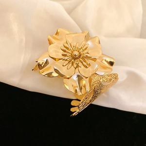 Detail shot of a polished gold flower bracelet on silk fabric with high metallic shine