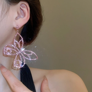 Detailed view of oversized pink butterfly drop earring with zircon crystals on model