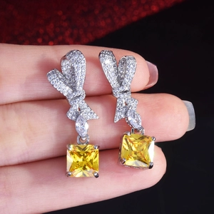 Detailed shot of radiant cut yellow gemstone earrings with sparkling bow design