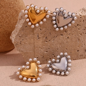 Detail shot of heart-shaped earrings with gold and silver plating and pearl edges