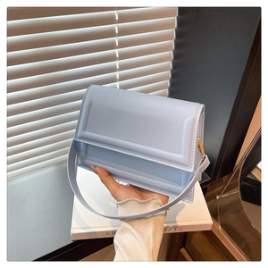 Fashionable light blue square bag shown held by a model in soft window lighting