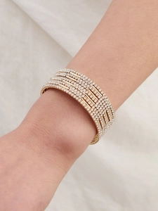 Macro detail of multi-row gold plated bracelet with sparkling rhinestone inlay