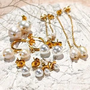 Detailed collection of gold plated stainless steel freshwater pearl earrings on stone