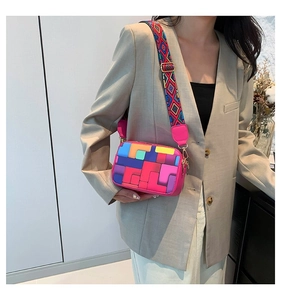 Model wearing a colorful geometric crossbody bag with magenta edges and a wide woven strap