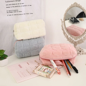 Quilted cloud cosmetic bags in pink, blue, and cream white on a desk with stationery