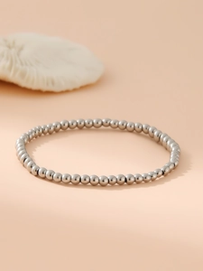 Dettaglio del bracciale con perline in acciaio inossidabile argento su fondo sobrio