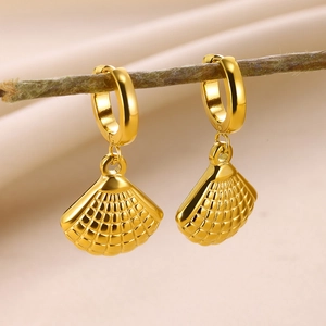 Détail de boucles d'oreilles coquillage en or 18K suspendues à une branche naturelle