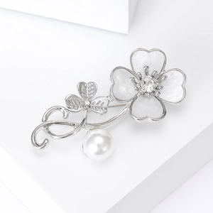 Detailed close-up of shell four-leaf clover brooch with pearl pendant and crystal accents