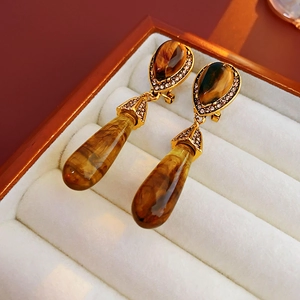 Close-up of vintage tiger eye drop earrings with diamond accents in a jewelry box