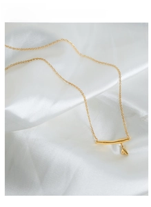 Détail d'un pendentif bambou doré avec breloque feuille sur satin pour collier chic