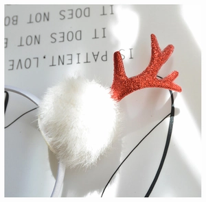 Close-up of red sequined reindeer antlers and white plush pompoms on Christmas headband