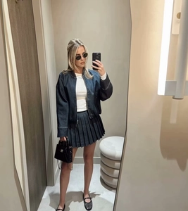 Dettaglio di una minigonna a pieghe in denim scuro con elegante design a vita media