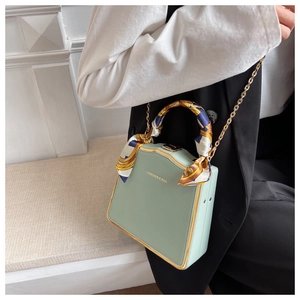 Detail of mint green box bag with printed silk scarf handle and golden metal frame