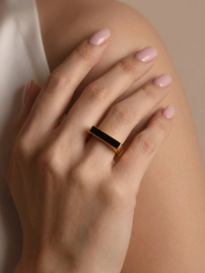 Close-up of minimalist gold square ring with black enamel inlay on a model hand