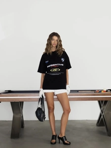Μαύρο oversized T-shirt με λευκά γράμματα σε μοντέρνο σκηνικό δρόμου με αίσθηση street style