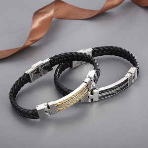 Close-up of woven black leather bracelets with gold and silver steel cable details
