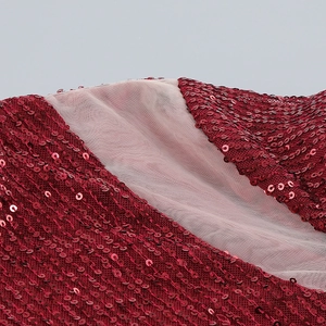 Détail macro de paillettes rouges scintillantes et tulle fin sur une robe de soirée