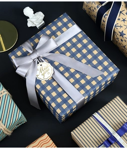 Close-up of blue plaid kraft gift wrapping paper with a wide silver grey satin ribbon bow