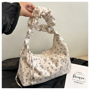 Close-up of floral drawstring handbag with detailed pleated handles and cream base