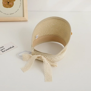 Detail of children straw sun hat featuring a beige lace bow and woven texture detail