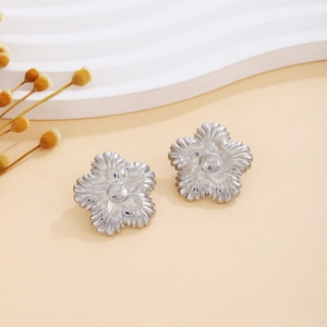 Detail of silver floral earrings with radiant textured petals and central bud on wavy stand
