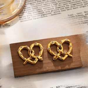 Detail of 18K gold stainless steel heart-shaped knotted earrings with sparkling stones