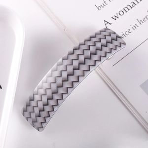 Detail of a rectangular acetate hair clip featuring a black and white woven pattern