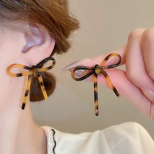 Close-up of leopard print bow earrings with amber resin texture on model ear