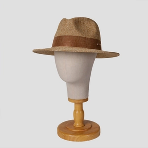 Close-up of woven straw fedora featuring a brown fabric band and small metal plate