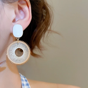 Close-up of golden dreamcatcher hoop earrings with white thread weaving and beads
