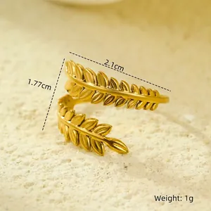 Macro shot of gold olive leaf ring with multi-layer structure on beige sand background