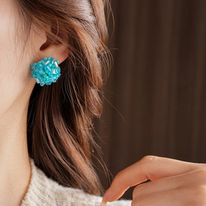 Close-up of blue beaded cluster earrings on a model, showing stylish round stud details