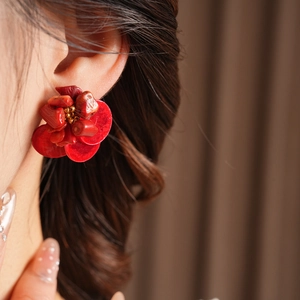 Close-up of vintage red flower earrings with coral-like beads and gold metallic center