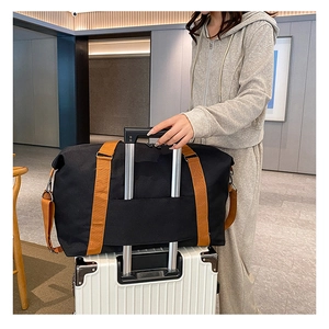Black duffel bag with trolley sleeve attached to a white suitcase in a modern interior