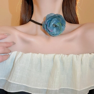 Detail of blue lace fabric flower choker with long black neck ties on a model's neck